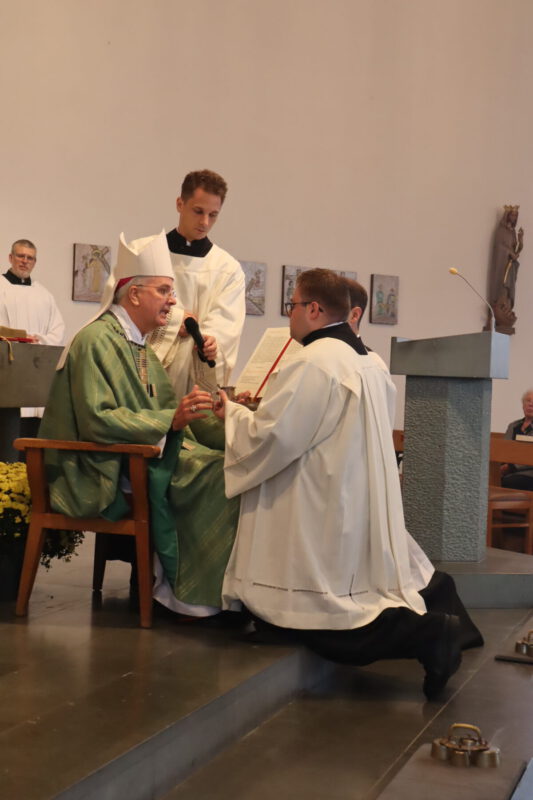 Der Weihbischof überreicht Balcarczyk die Schale mit Brot und den Krug mit Wein