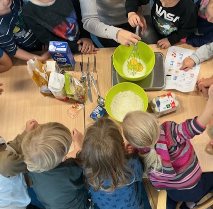 Kinder machen mit Erzieherin einen Teig 